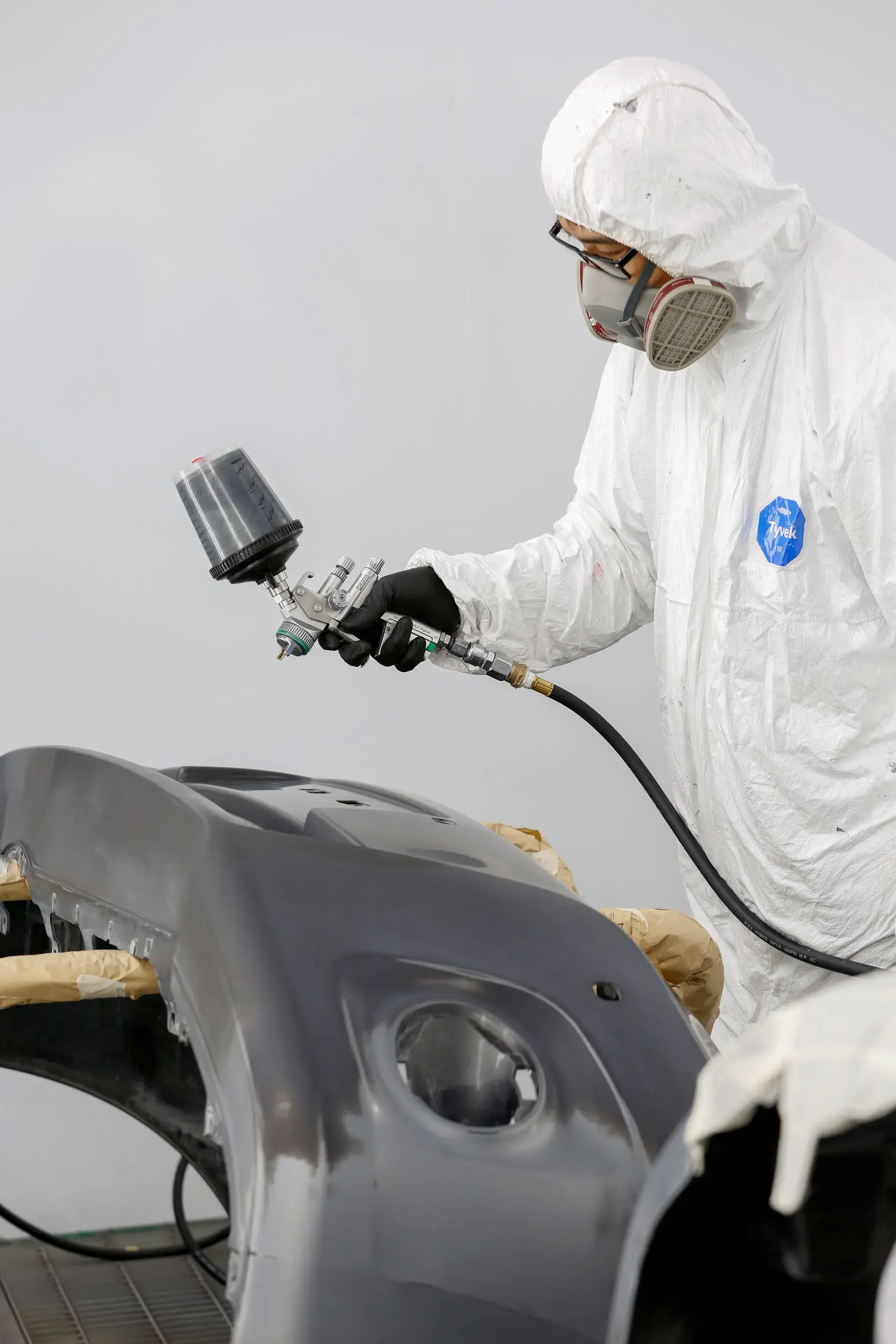 Technician spray-painting an automotive body panel